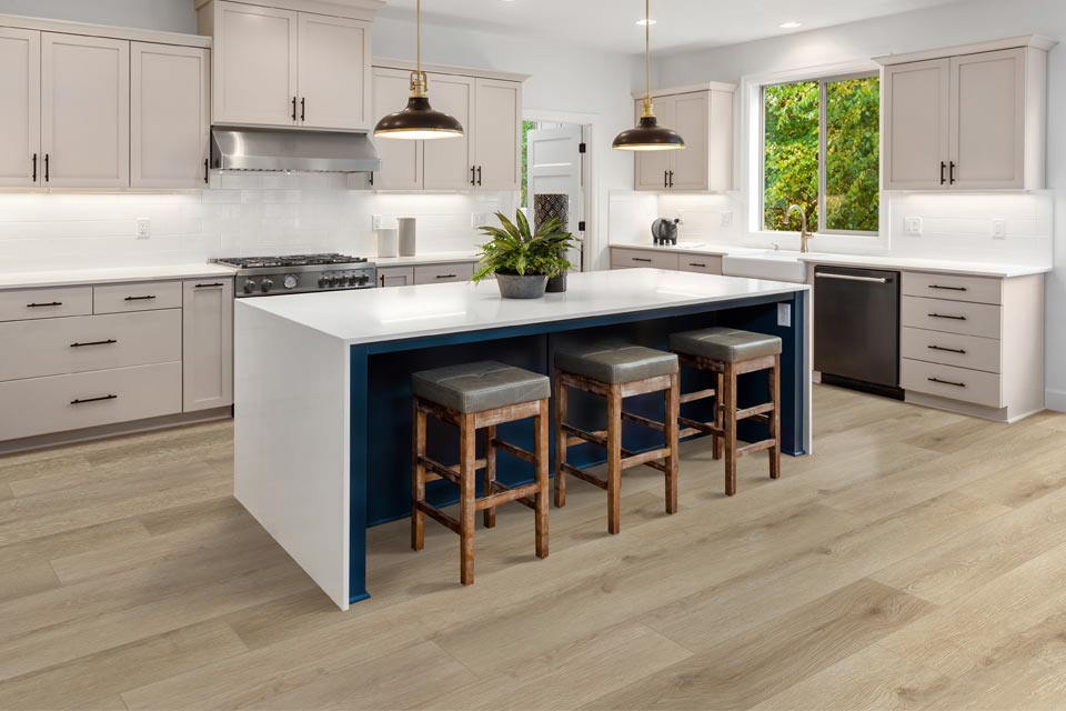 warm toned wood look vinyl flooring in kitchen with white cabinets and kitchen island with wood stools and mixed metal decor.